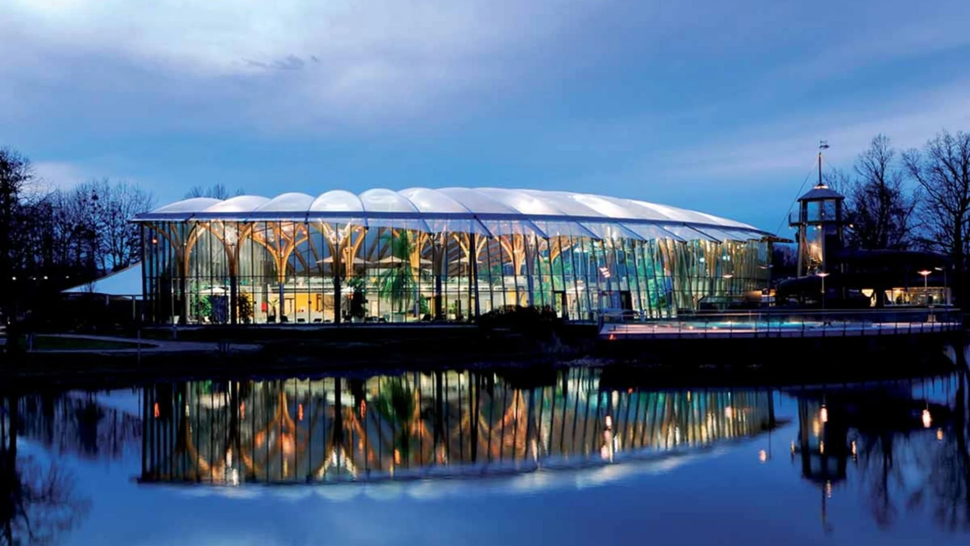 Modern glazen gebouw met reflecterend water bij schemering
