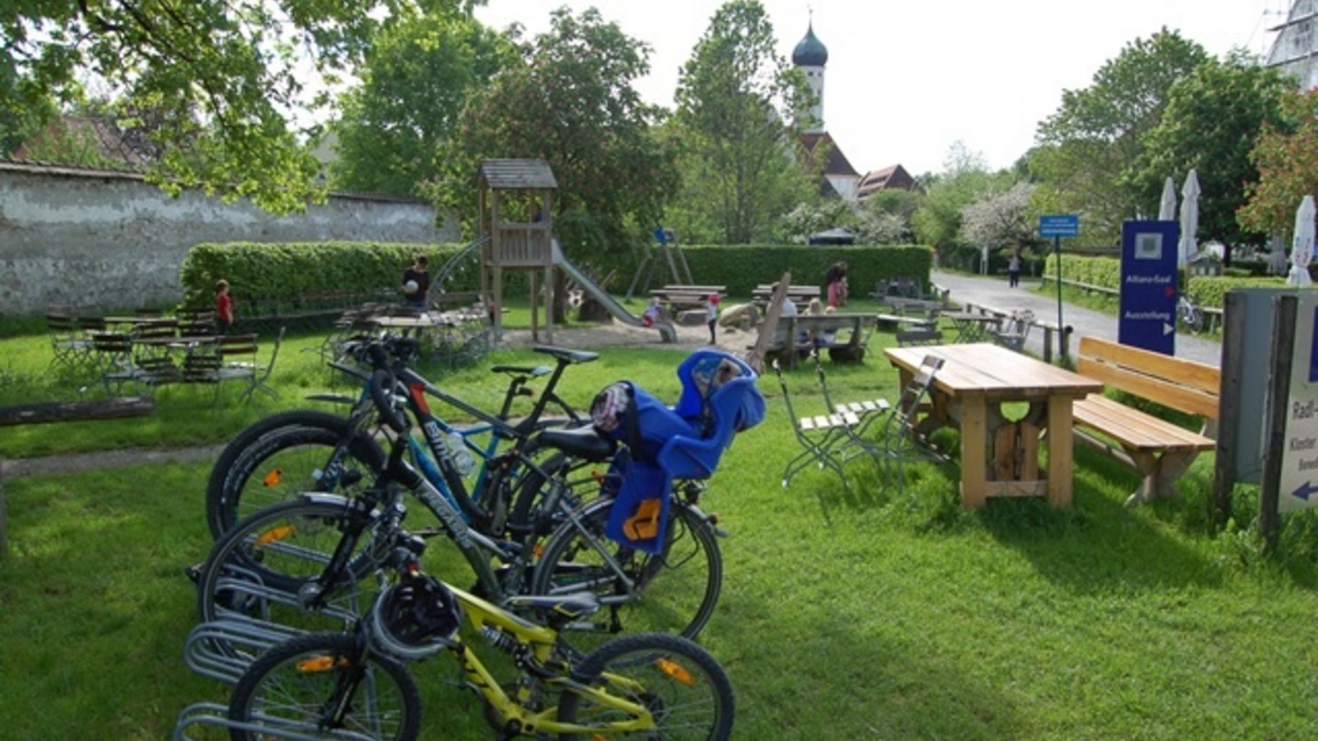 Bicycles with child seat near playground and seating area in park