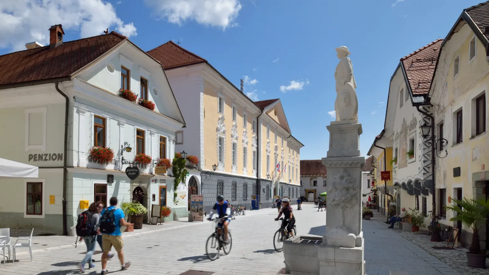 Fietsers en voetgangers op een zonnig historisch Europees dorpsplein