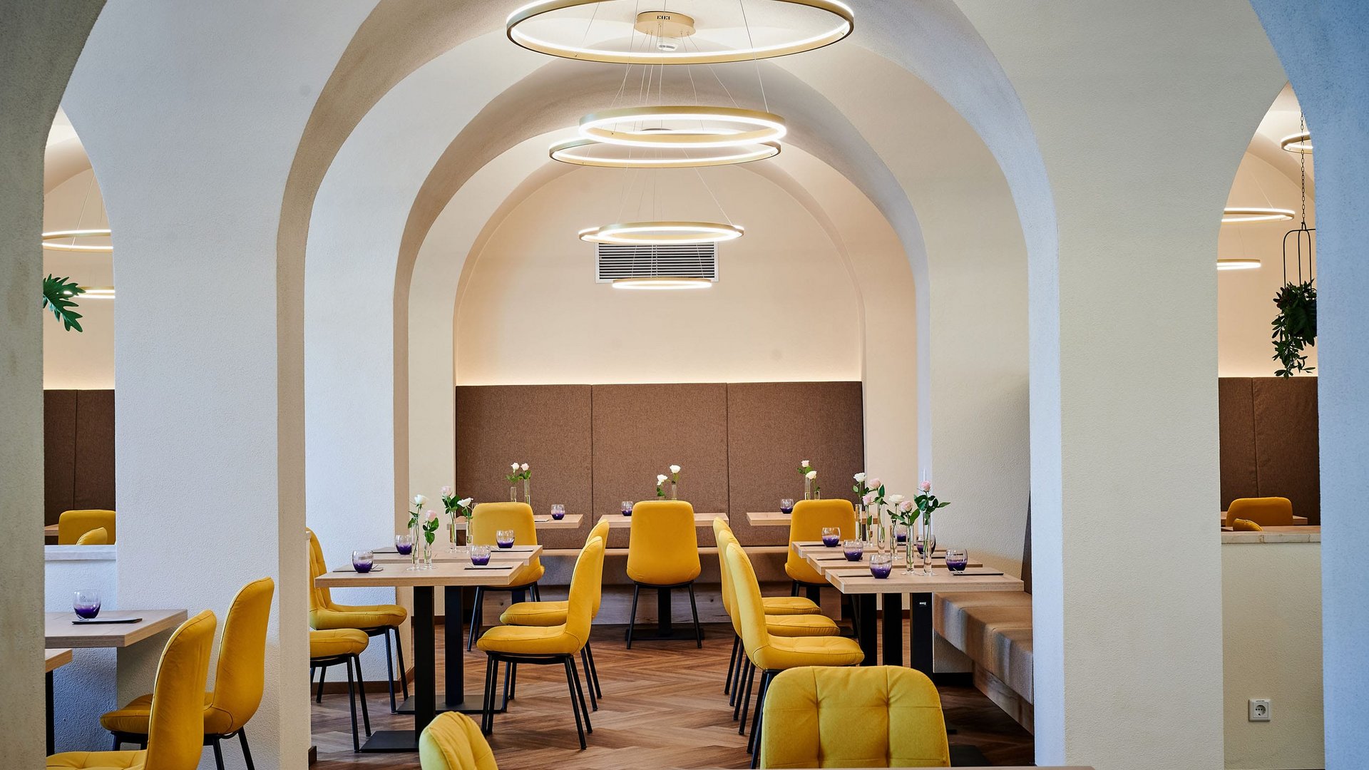 Modern restaurant interior with yellow chairs and white arched walls