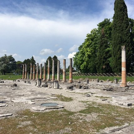 Roman columns and ruins at an archaeological site under a cloudy sky