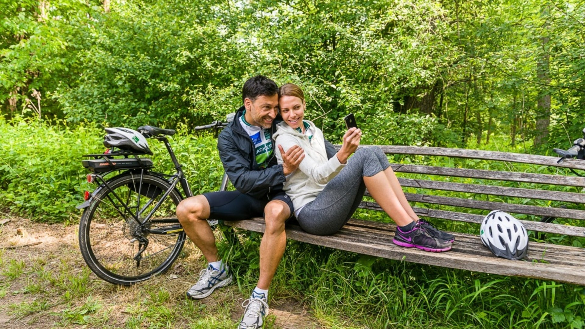 Couple taking selfie on park bench after bike ride