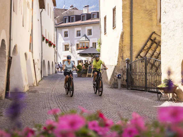 Ein Genuss-Radtag am Reschensee © Heiko Mandl Zwei Radfahrer fahren durch eine malerische Gasse einer alten Stadt