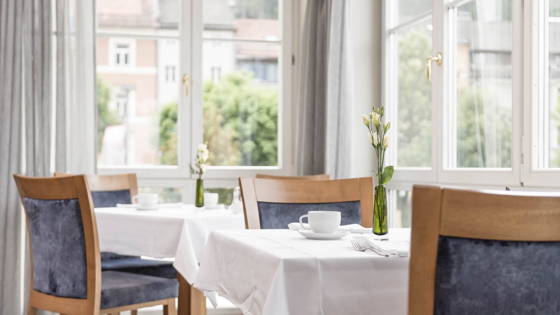 Bright breakfast room with white tablecloths and small flower vases