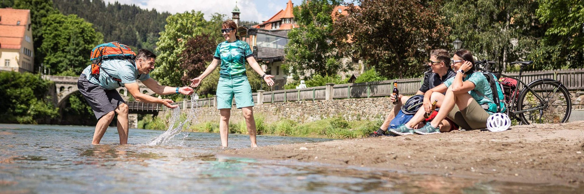 Freunde entspannen und spielen am Flussufer an einem sonnigen Tag.