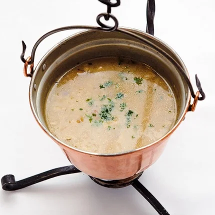 Soep geserveerd in een koperen pot op een standaard