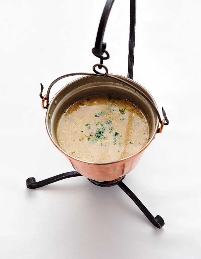 Soep geserveerd in een koperen pot op een standaard