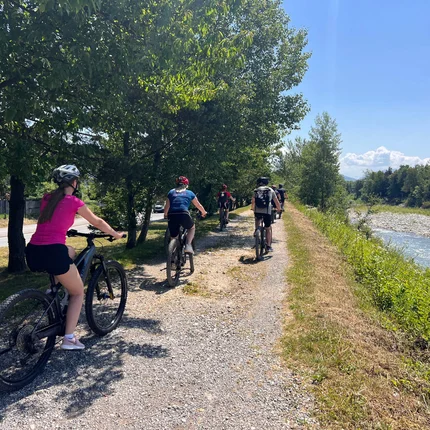 Groep fietst op schaduwrijk pad langs rivier bij zonnig weer