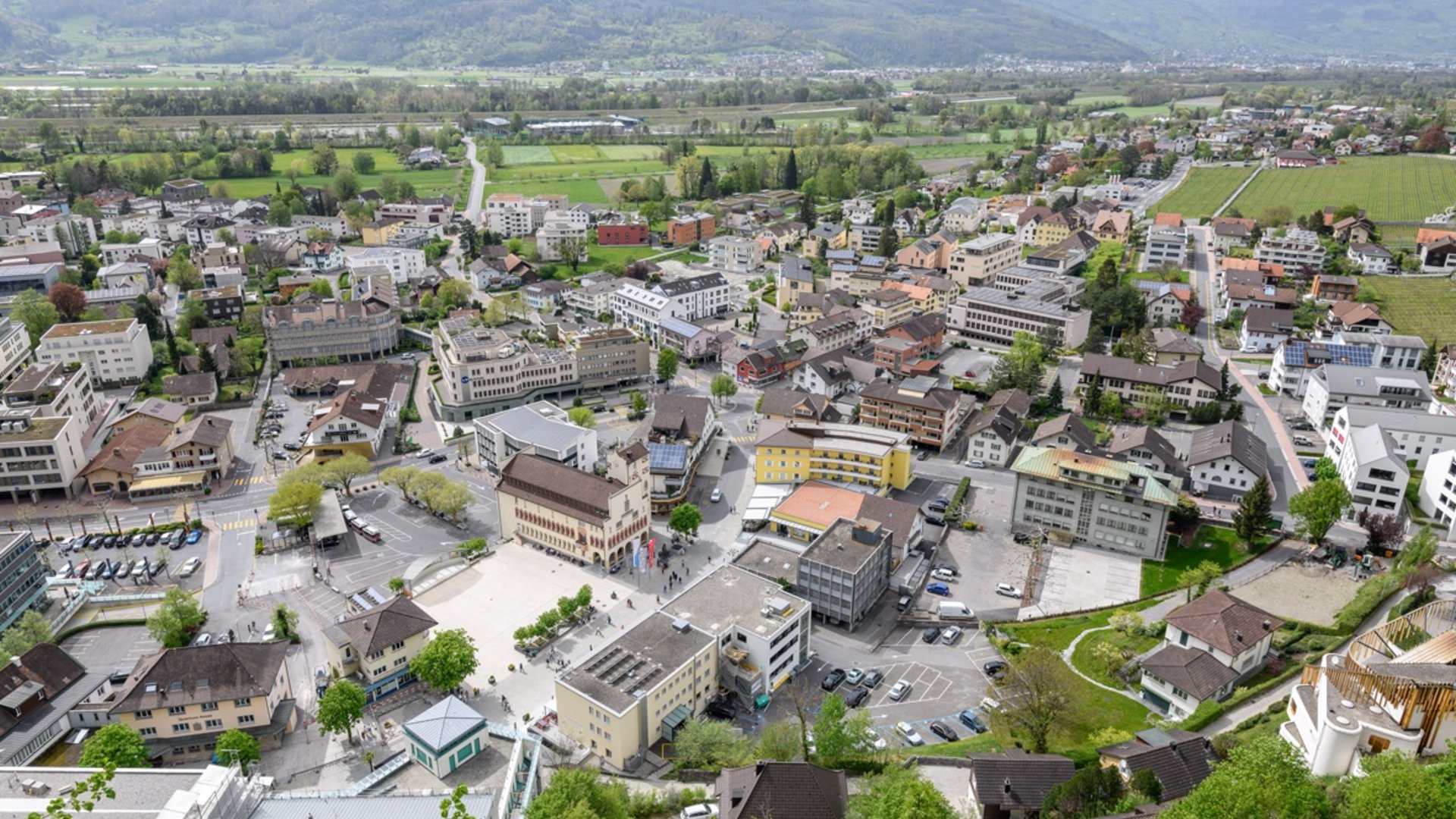 Aerial view of a small town with mountains and green fields in the background