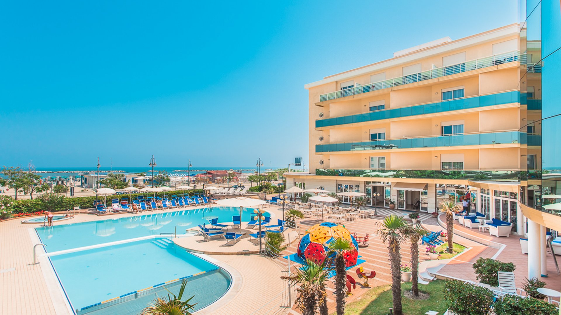 Hotel with outdoor pool, sun terrace, and playground by the sea