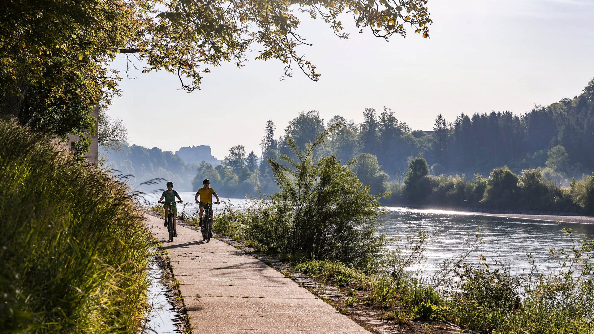 Two people cycling on a path along a river