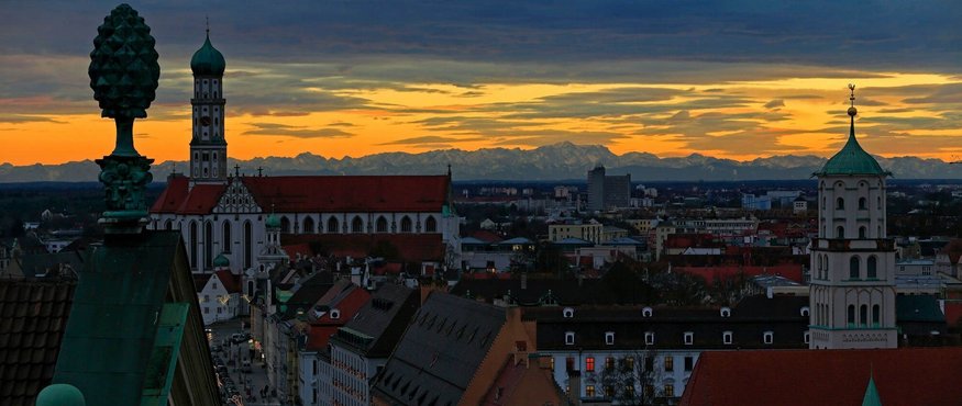 Augsburg cityscape at sunset with Alps in the background