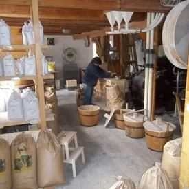 Persoon aan het werk in een traditionele molen met zakken en houten emmers