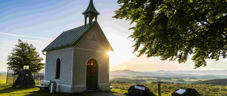 Small chapel at sunset with landscape and trees in the background