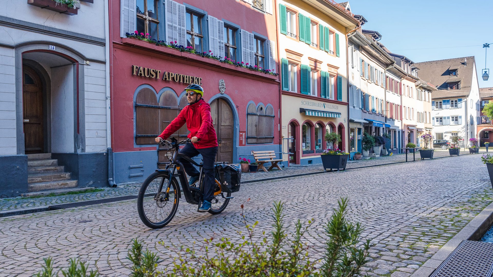 Man riding bicycle on cobblestone street in old town