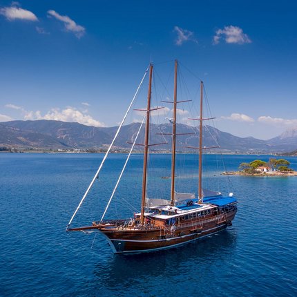 Kultur, Natur und Meer auf Rad- & Schiffsreisen © Radurlaub Zeitreisen Segelschiff auf blauem Meer vor Insel und Bergen bei klarem Himmel