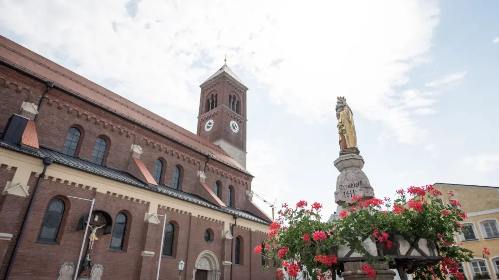 Kirchturm und Statue mit Blumen in historischer Altstadt
