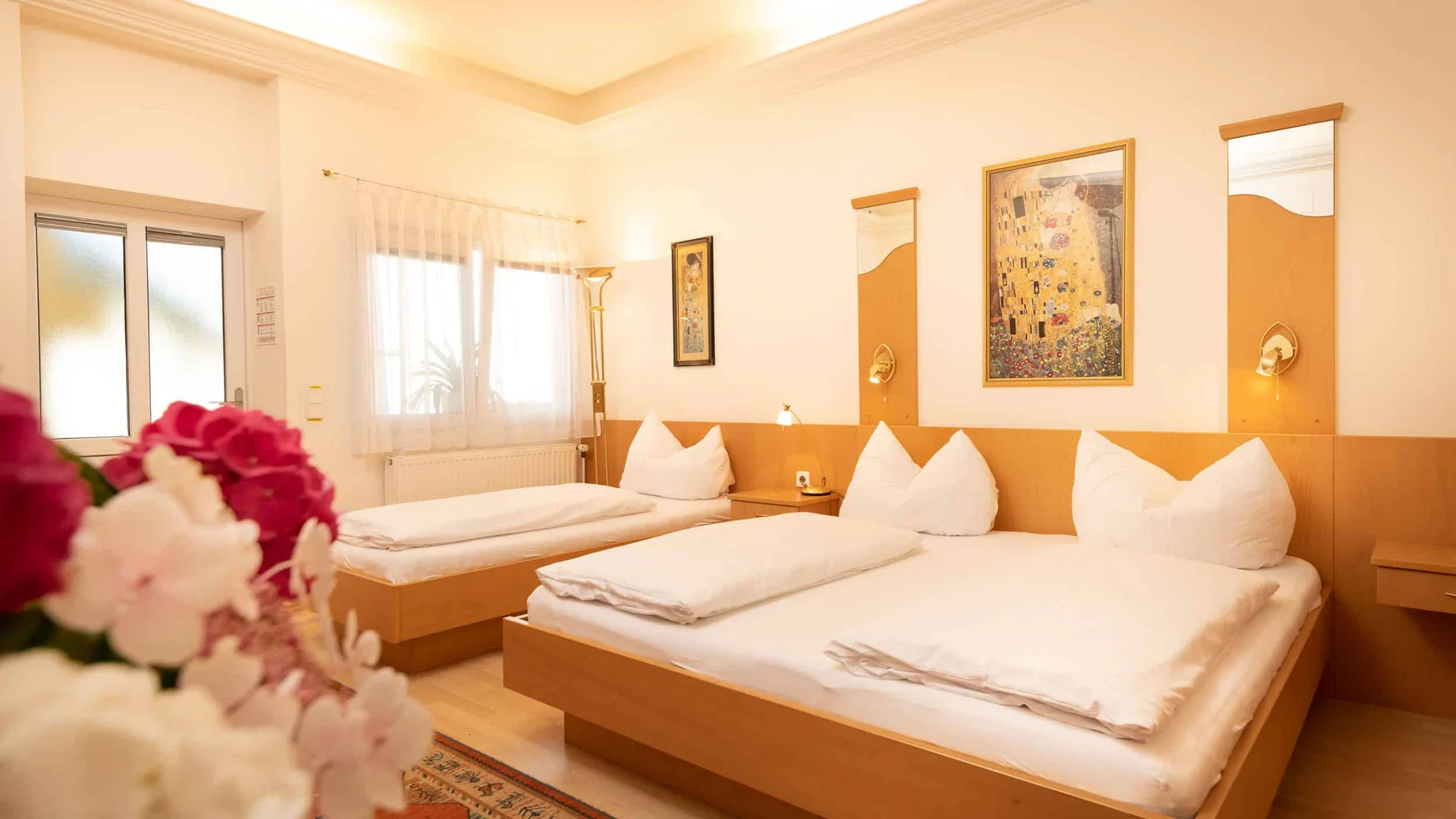Gezellige hotelkamer met twee bedden, bloemen en warme verlichting.