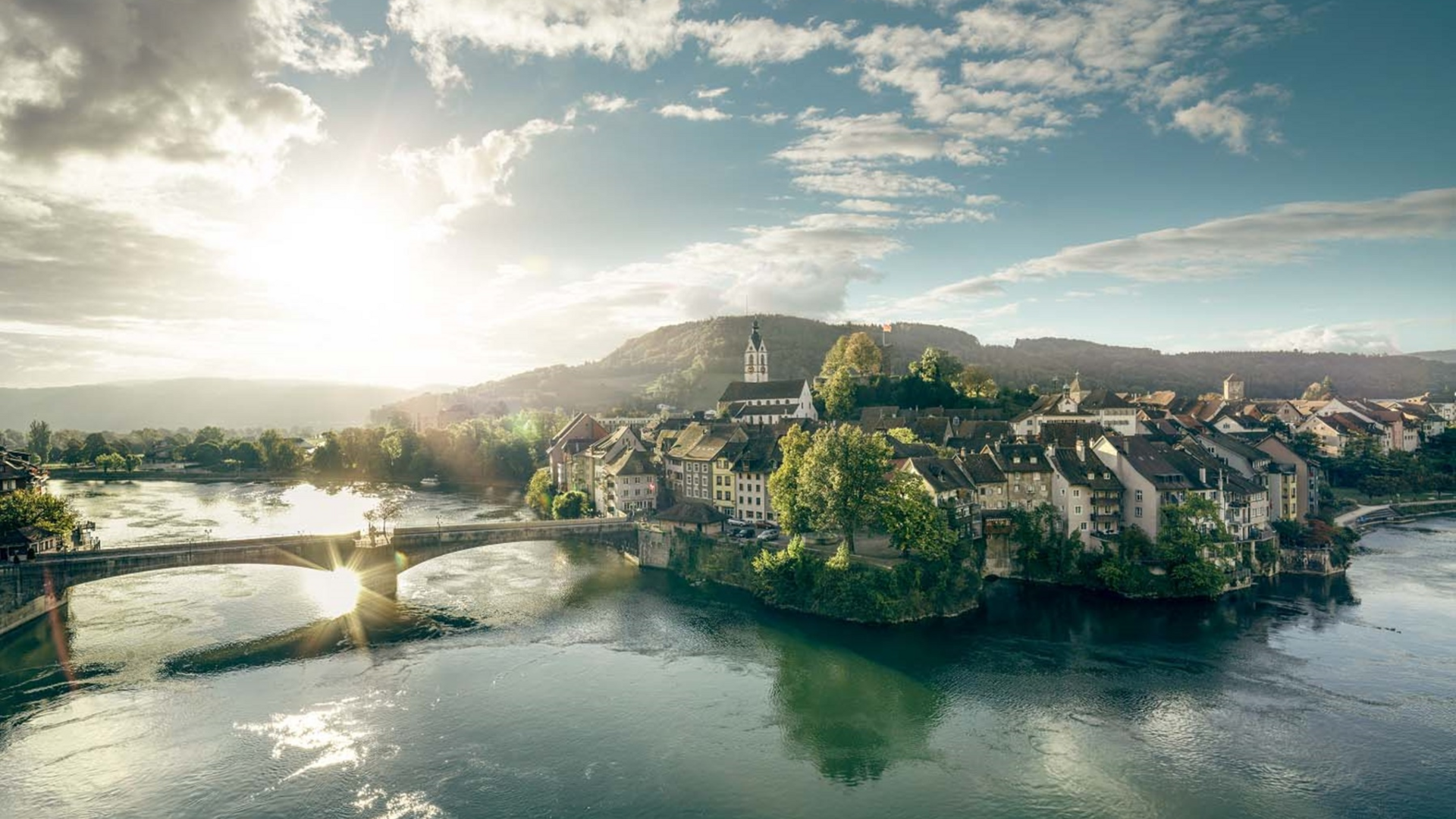 Sunset over a river bridge and village with church