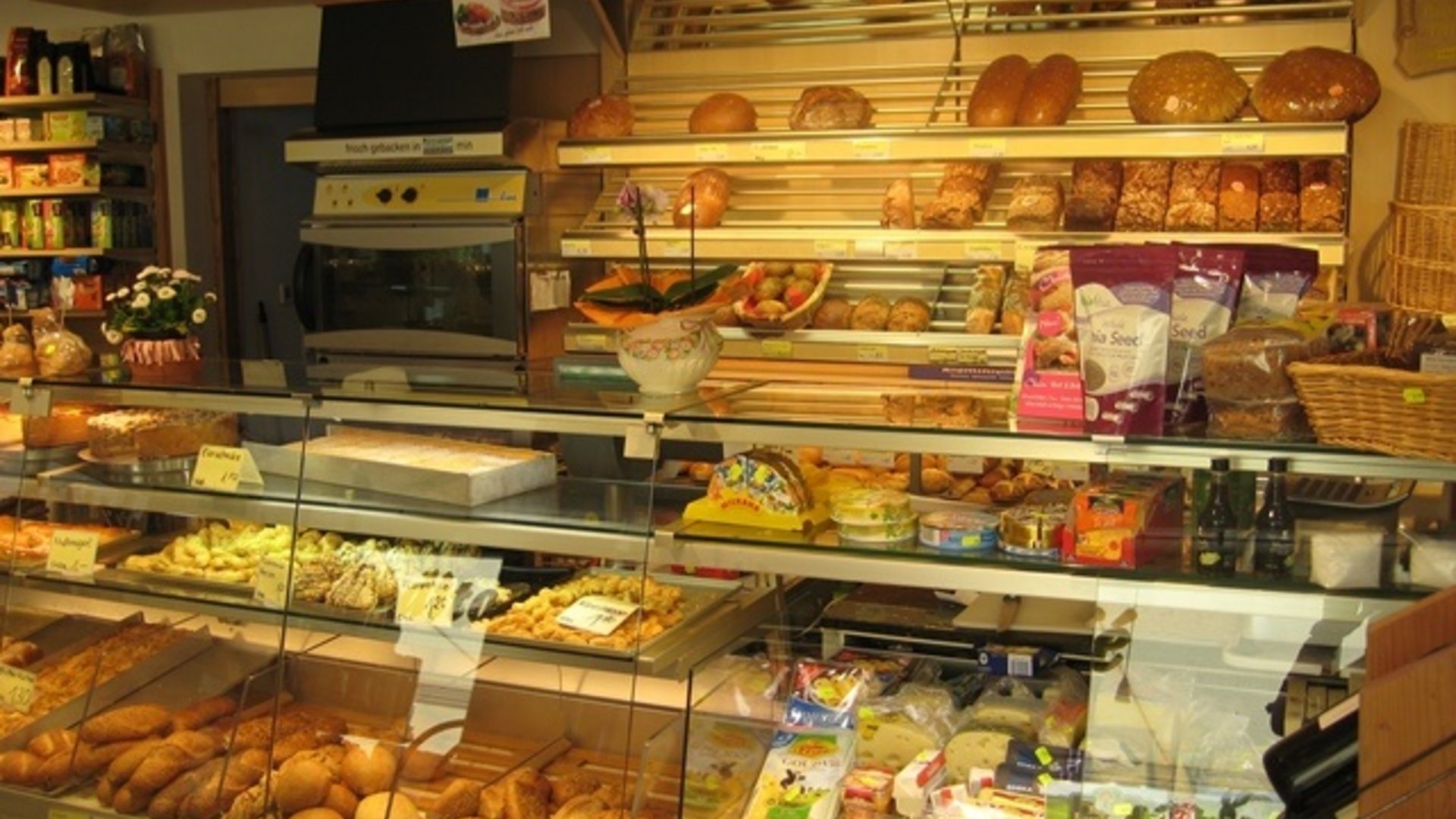 Bakery with various breads, cheese, and snacks displayed in glass case