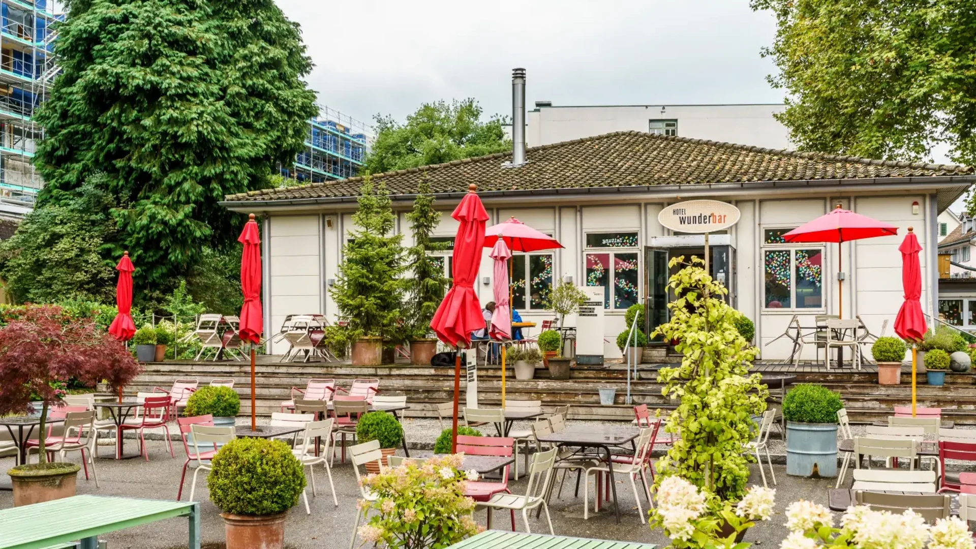 Buitenruimte van een café met tafels, stoelen en rode parasols