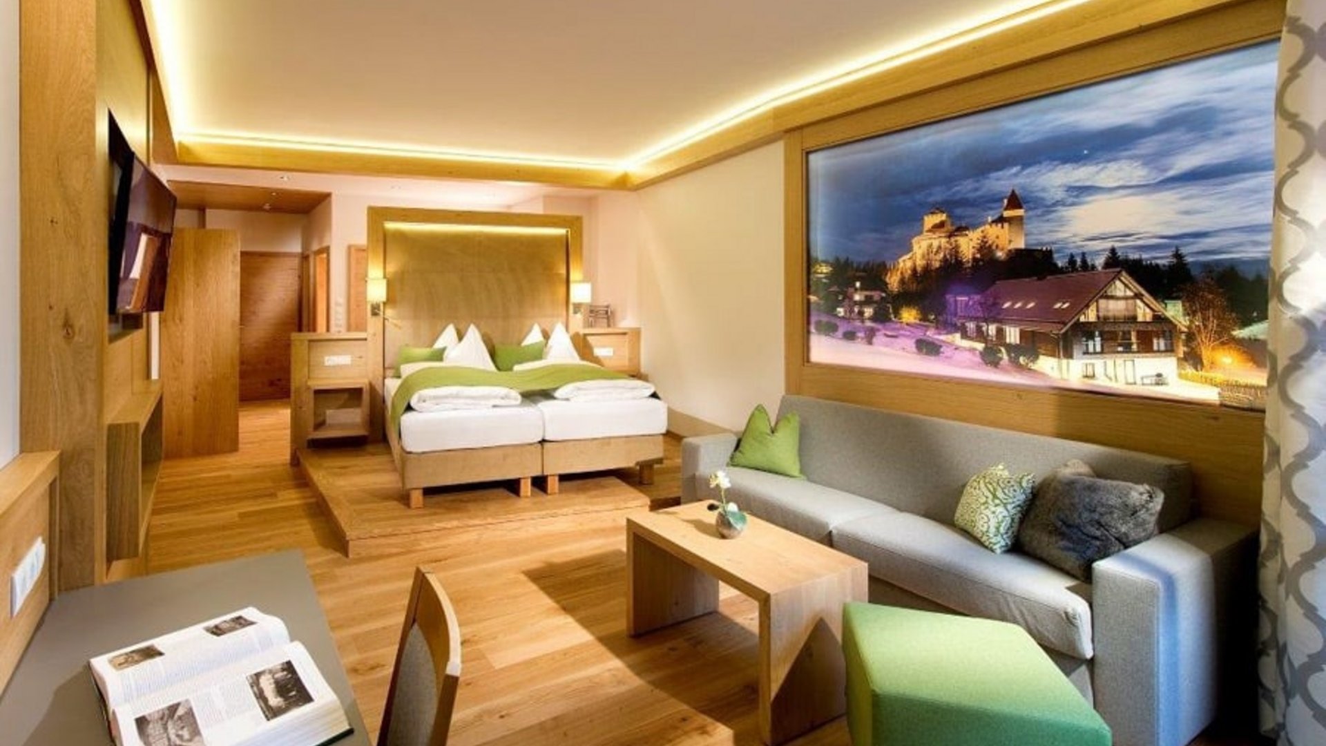 Modern hotel room with double bed, sofa, and large landscape painting