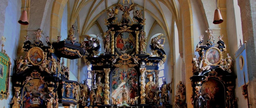 Interieur van een kerk met goudversierde beelden en schilderijen