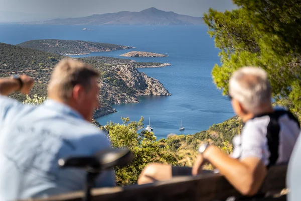 Kroatien: Entdecke das Land der 1001 Inseln mit Rad und Schiff! © Boat Bike Tours Zwei ältere Männer sitzen auf einer Bank und blicken auf eine bergige Küste und das Meer.