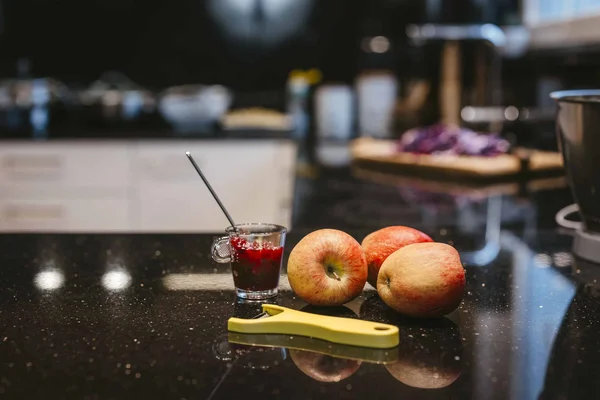 Süssmostcrème © Thurgau Bodensee Tourismus Frische Äpfel, Gelber Schäler und Glas mit roter Marmelade auf schwarzer Küchenarbeitsplatte