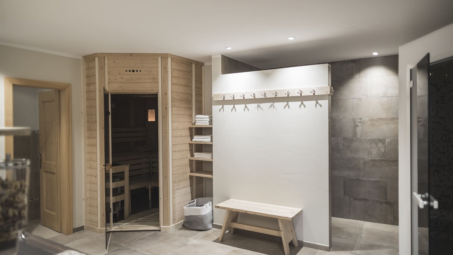 Modern changing room with wooden sauna, bench, and towels