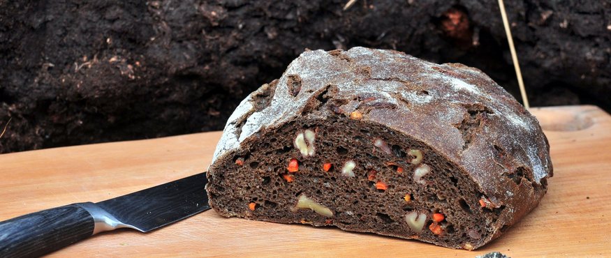 Moorbrot © TVB Anthering Dunkles Walnussbrot mit Karotten auf Holzbretter mit Messer