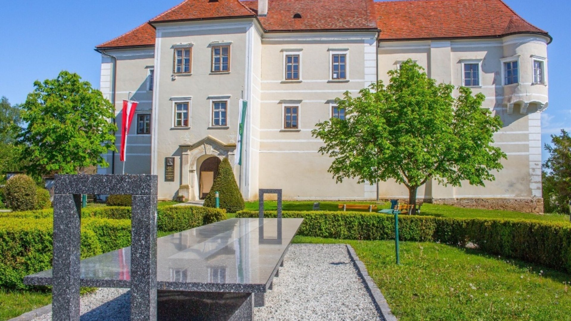 Castle with red roofs and modern stone table sculpture in the garden