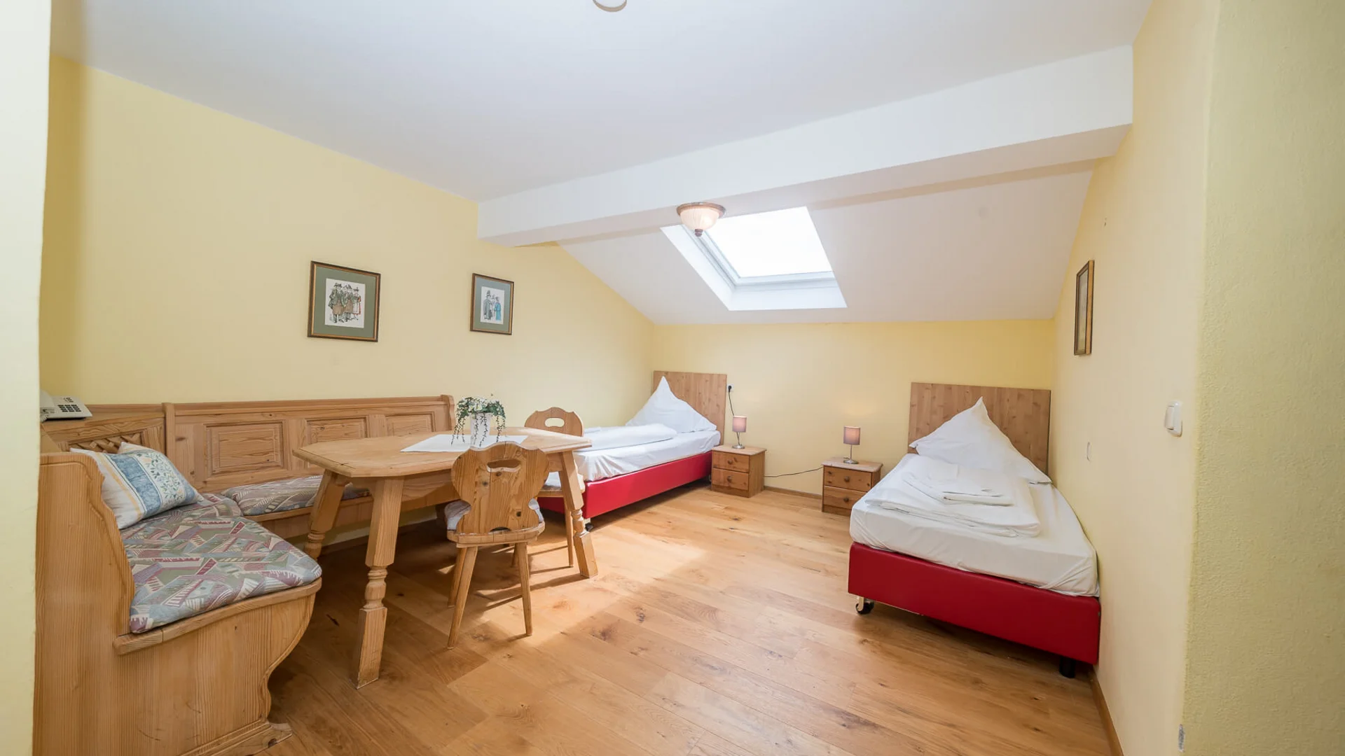 Bright bedroom with two single beds, wooden furniture and skylight