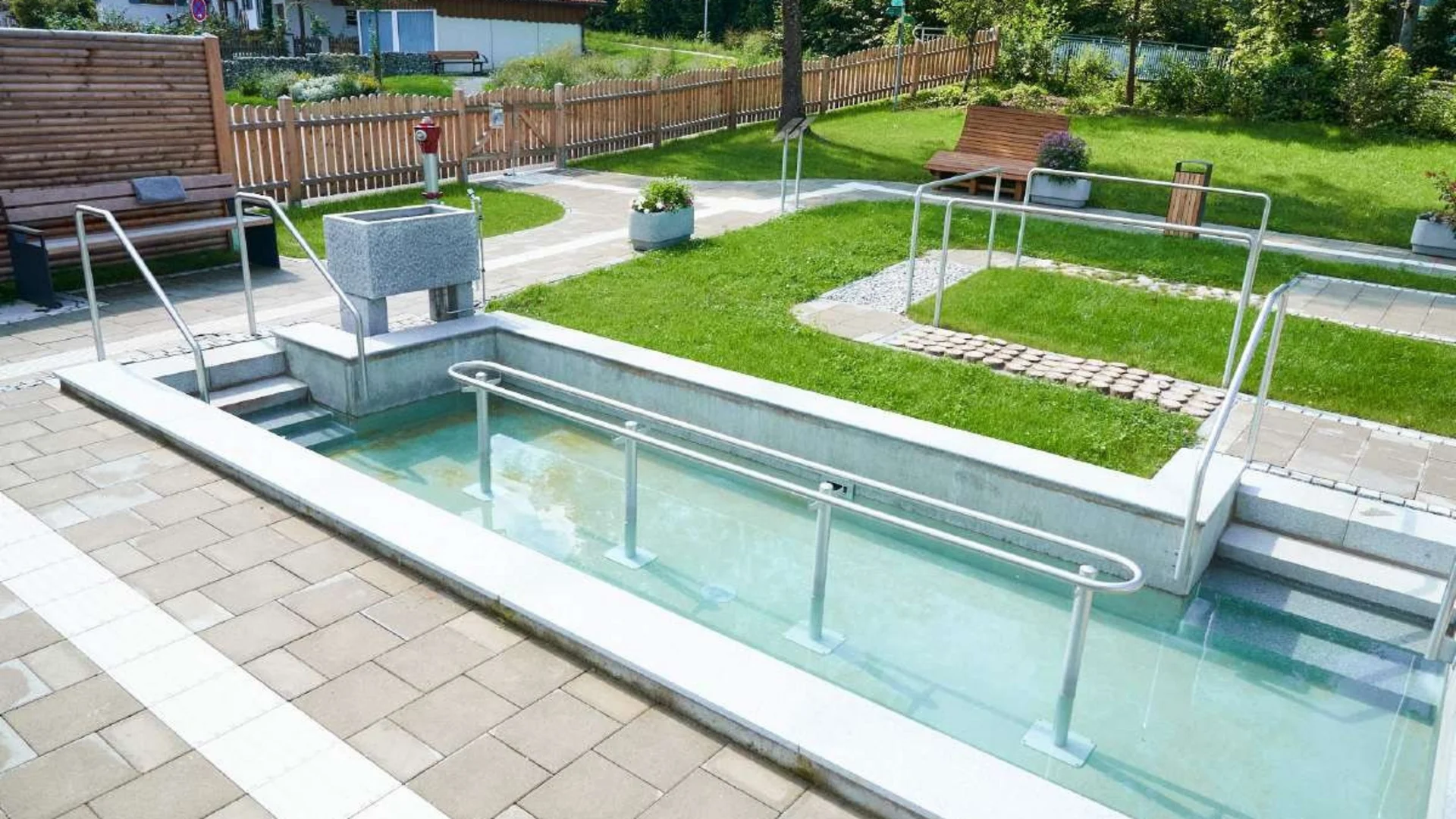 Kneipp-dompelbad en houten banken in zonnige tuin