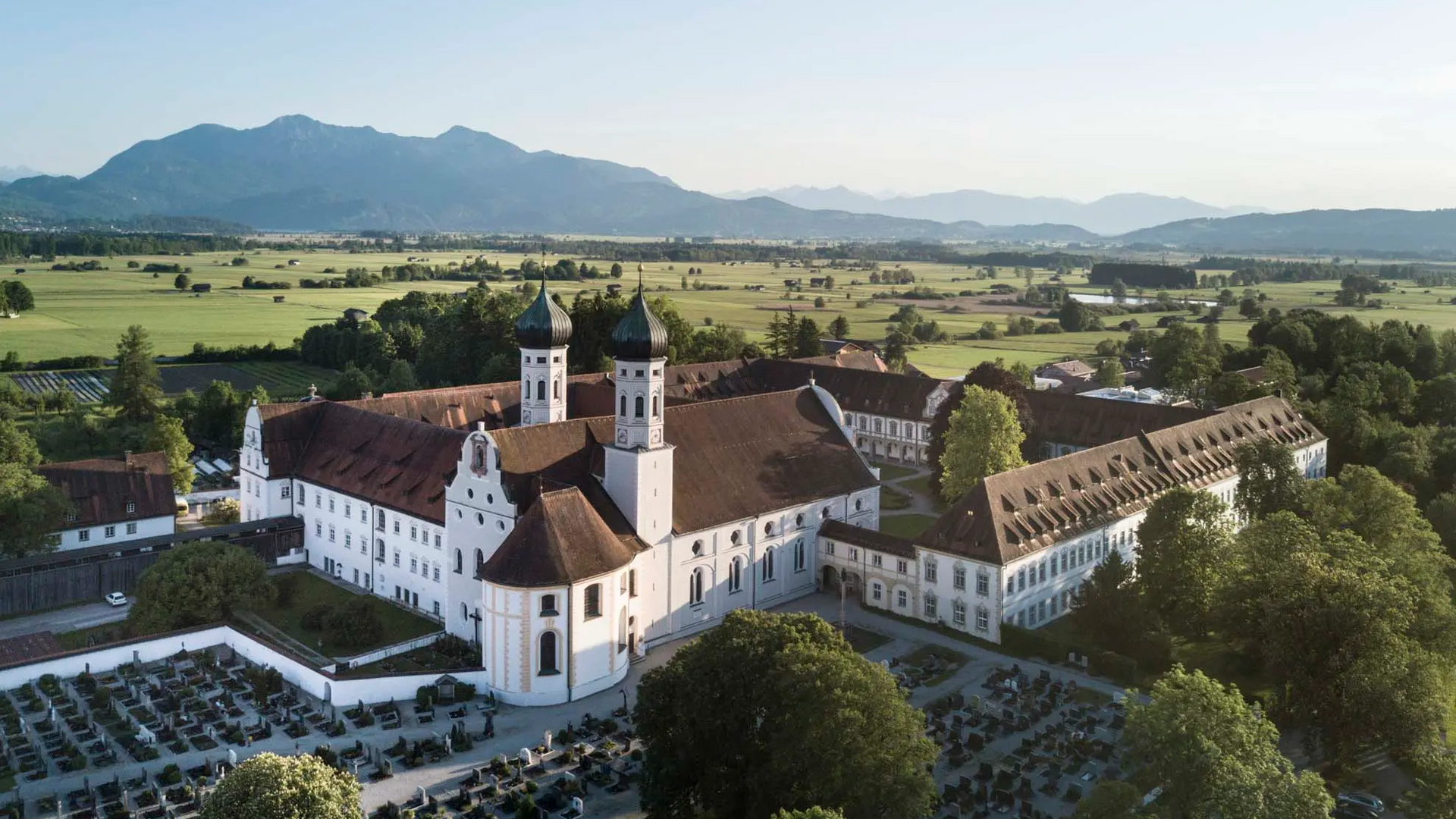 Aerial view of a historic monastery with mountains in the background