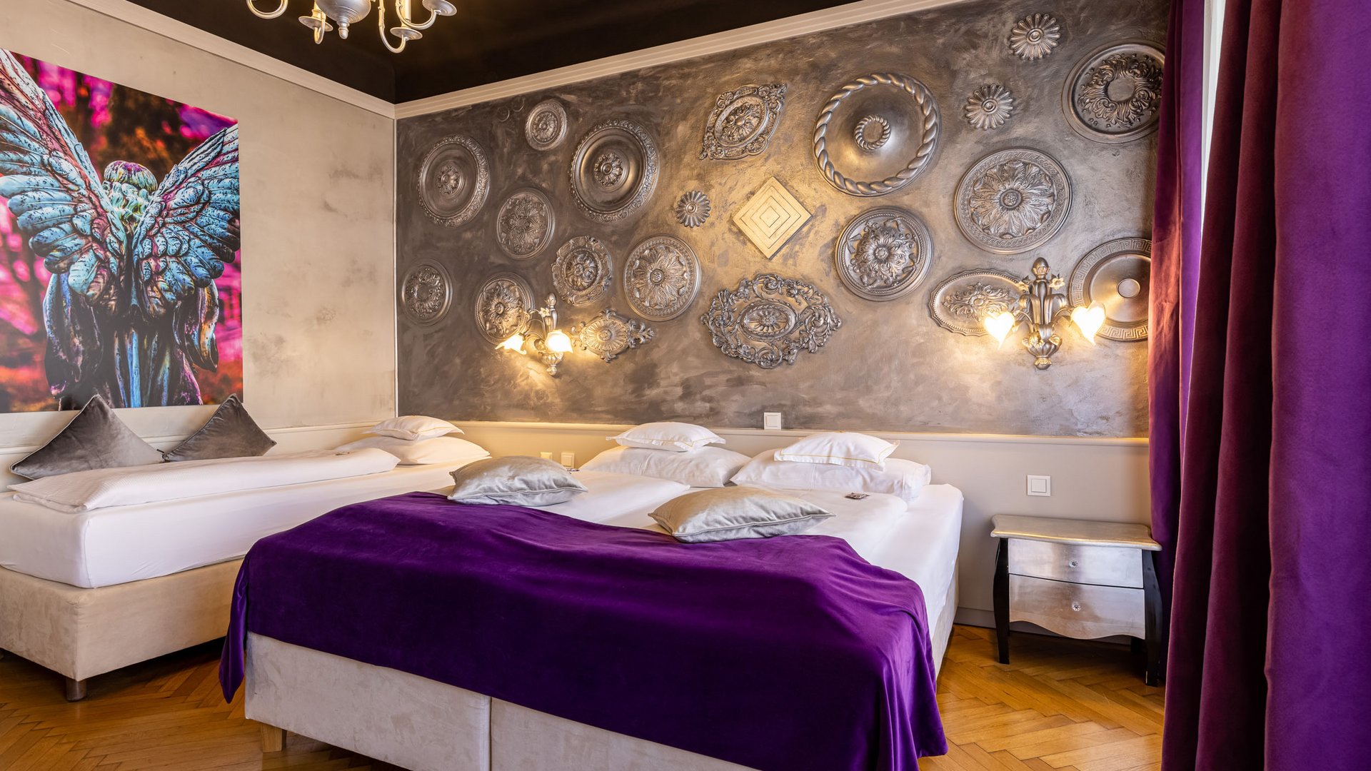 Bedroom with two beds, purple blanket and decorative wall art
