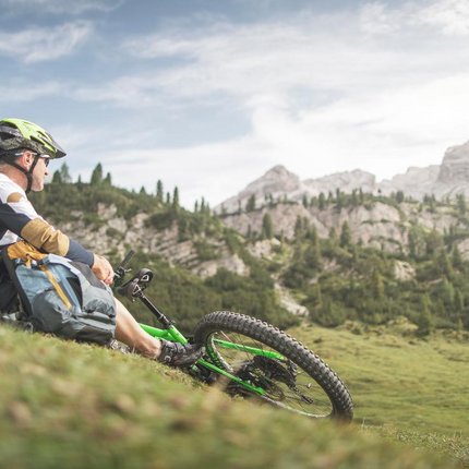 Mountain biker resting with green bike in mountainous landscape