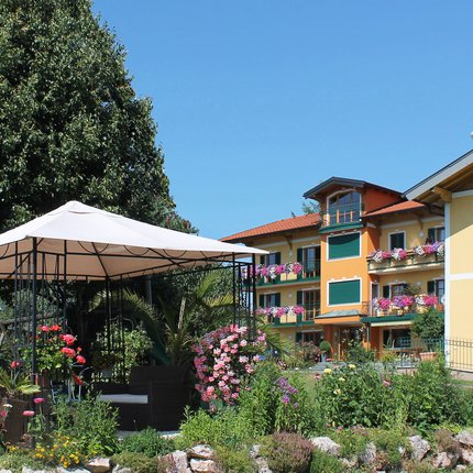 Garden with gazebo and colorful flowers in front of colorful residential building