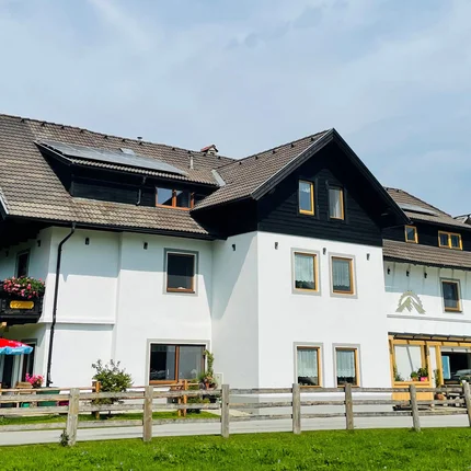 Großes weißes Haus mit braunem Dach und Berglandschaft im Hintergrund