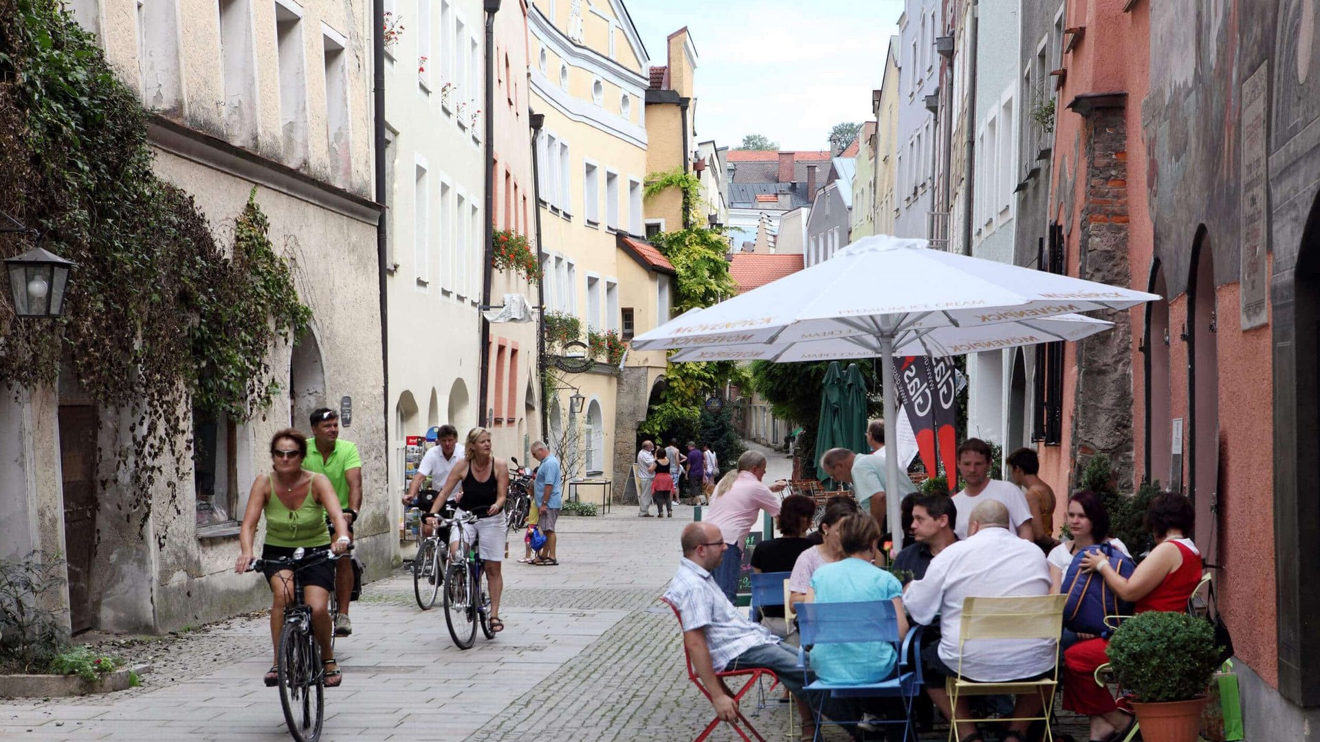 People cycling and sitting at a street cafe in a picturesque old town