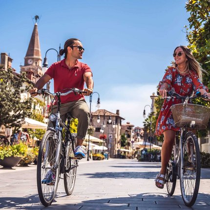 Paar fährt bei sonnigem Wetter mit Fahrrädern durch eine Altstadt