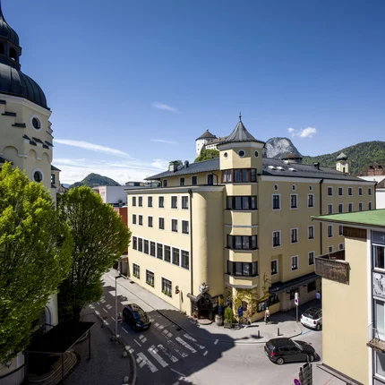 Historische Gebäude und grüne Bäume in einer sonnigen Stadt bei blauem Himmel