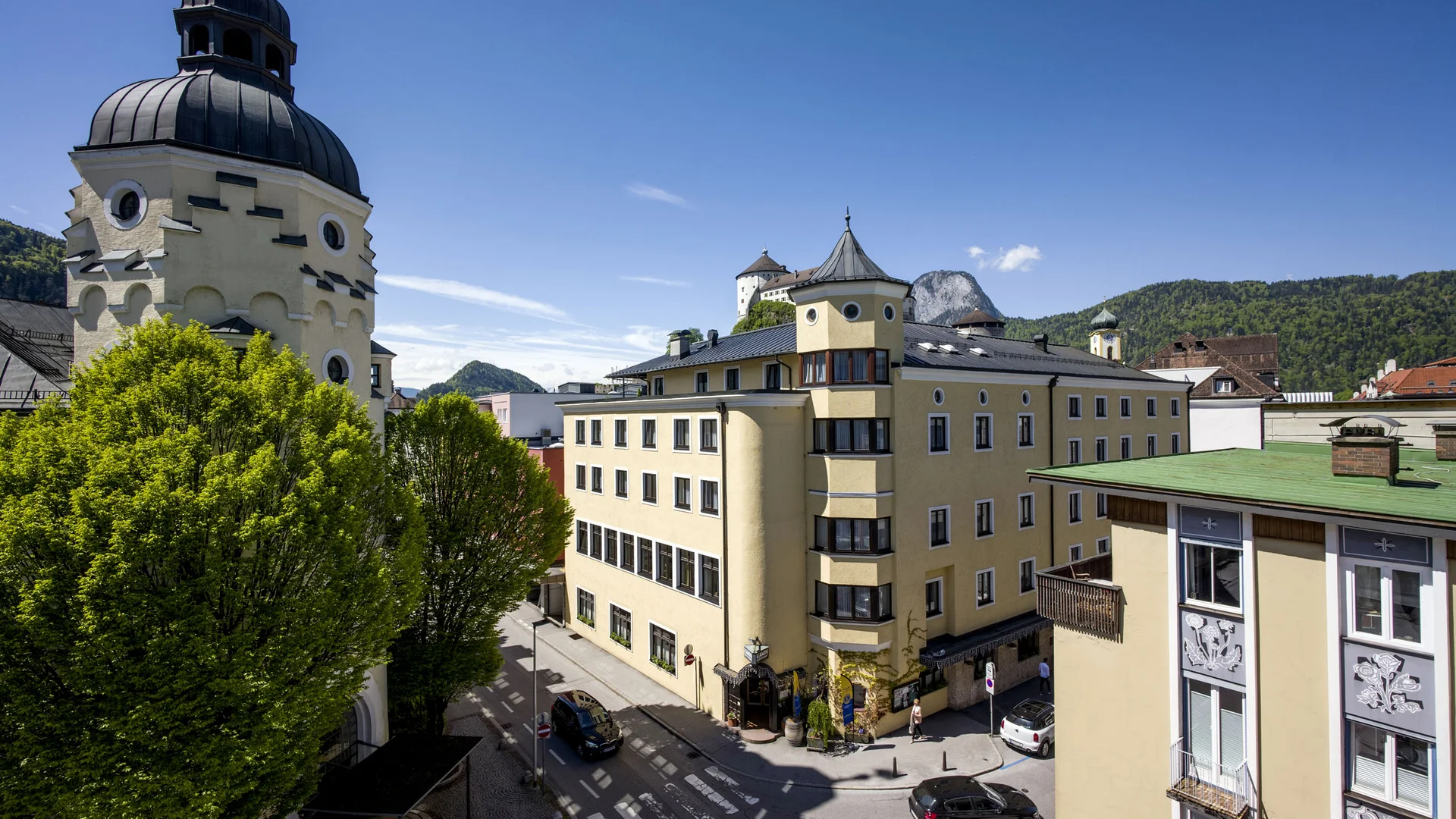 Hotel Andreas Hofer Kufstein **** © Hotel Andreas Hofer Kufstein Historische Gebäude und grüne Bäume in einer sonnigen Stadt bei blauem Himmel