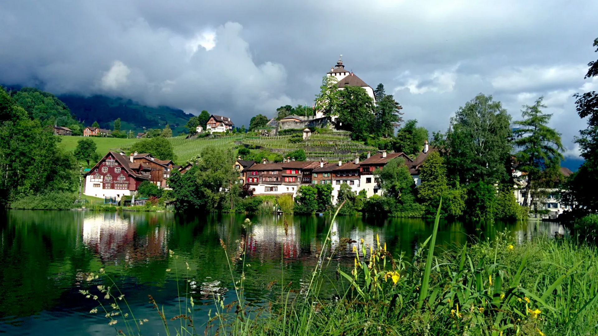 Mountain village with lake and old houses under cloudy sky