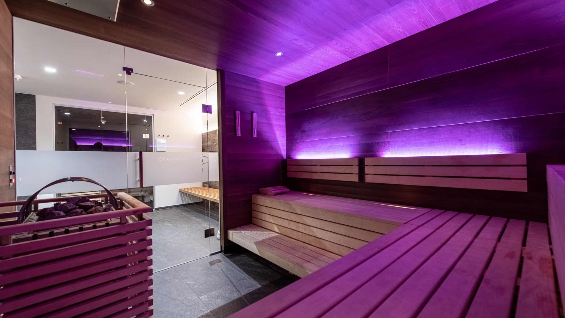 Modern sauna with purple lighting and wooden benches