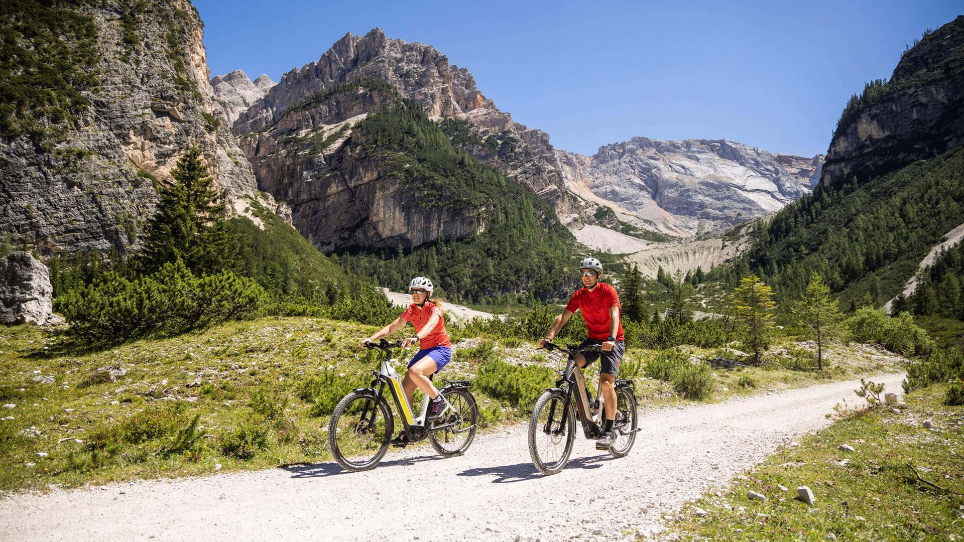 Two cyclists riding on a mountain path on a sunny day