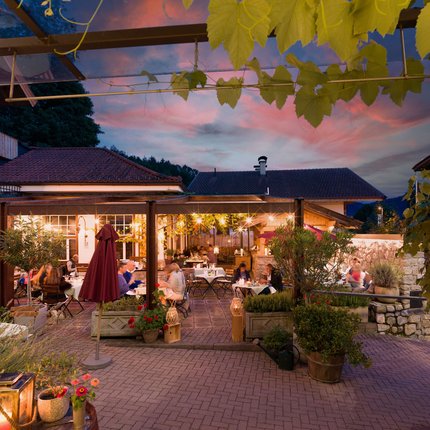 Dinner on a lit restaurant terrace with guests at sunset