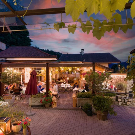 Dineren op een verlicht restaurantterras met gasten bij zonsondergang