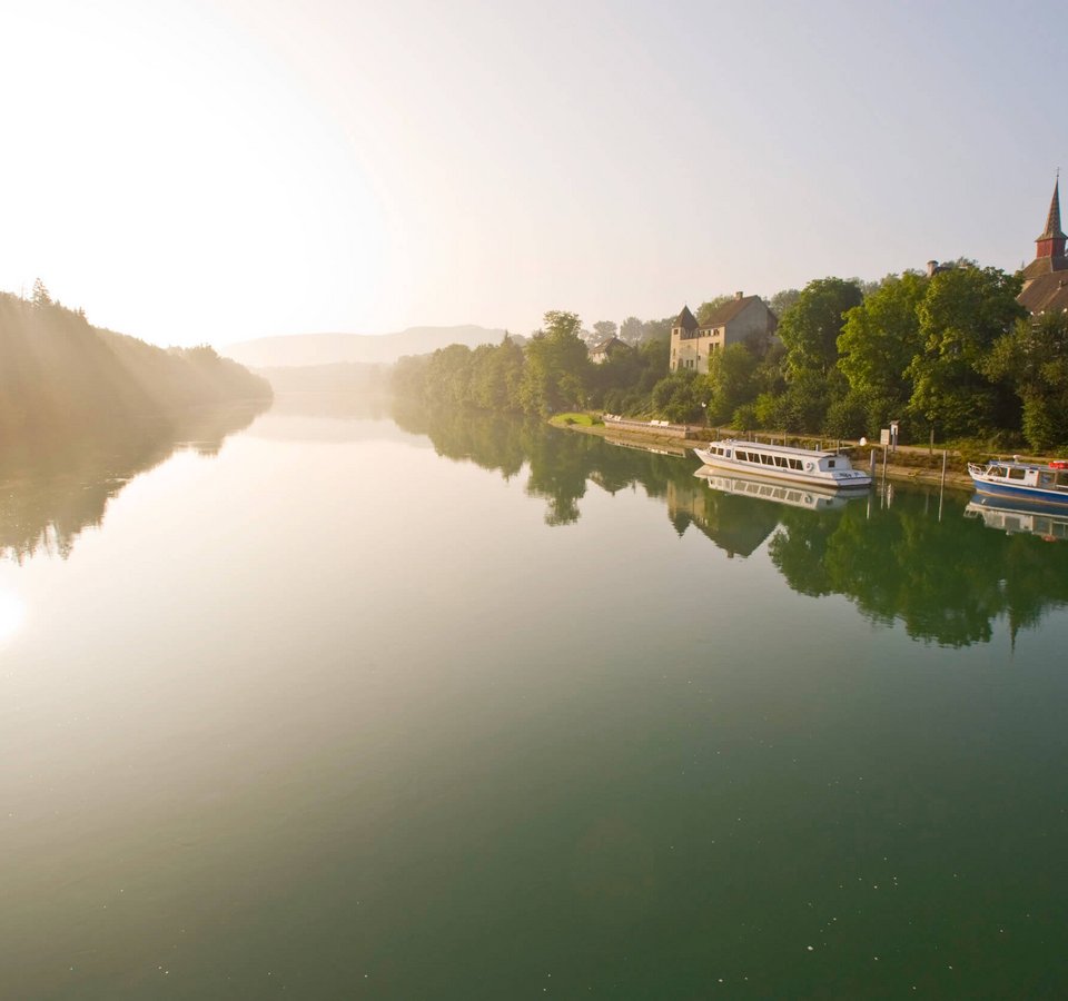 Fluss mit Booten und Stadt im Morgenlicht