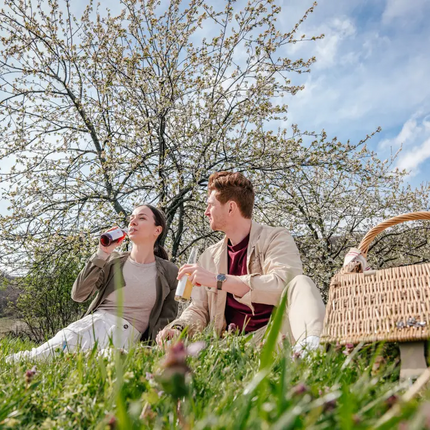 Couple sitting on grass drinking beverages during a picnic